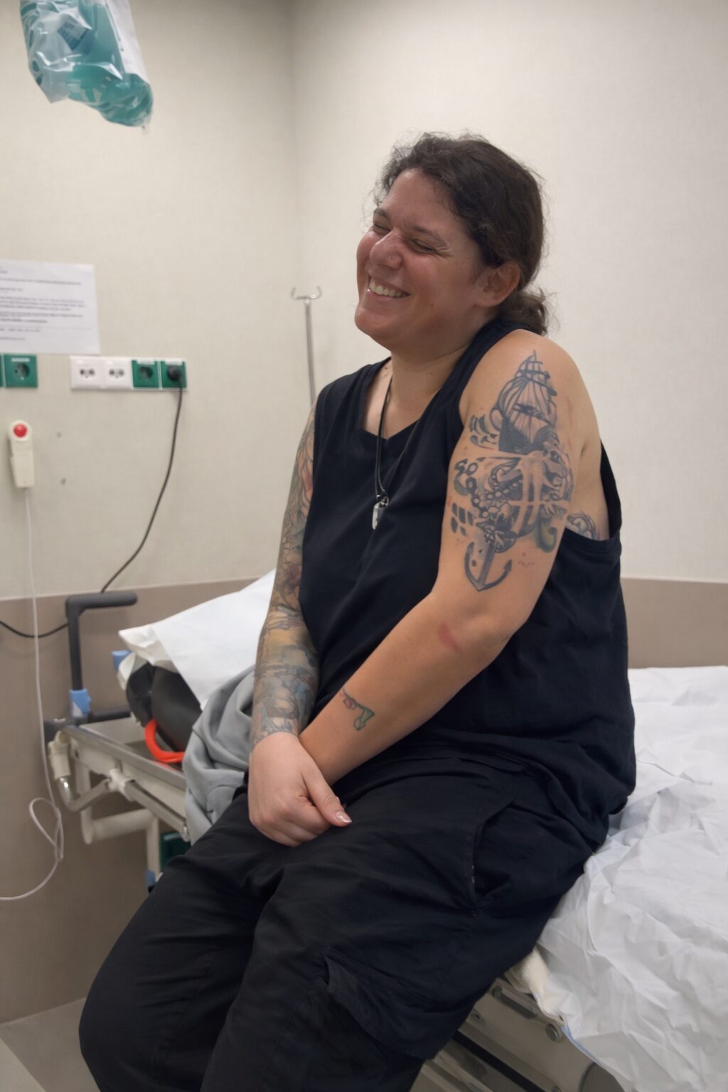 Solo traveler sitting on a hospital bed in the Netherlands after a hostel volunteering accident, holding her injured arm
